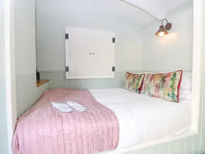 a bedroom with a bed with two towels on it at Damsel Shepherds Hut in Badwell Ash