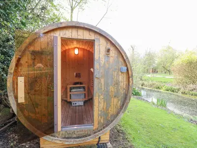 a large wooden barrel sitting in the grass at Damsel Shepherds Hut in Badwell Ash