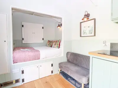 a small bedroom with a bed and a chair at Damsel Shepherds Hut in Badwell Ash