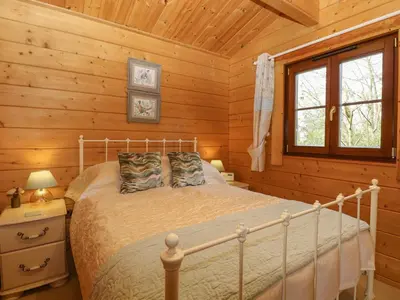 a bedroom with a bed in a log cabin at Heron Lodge in Langham