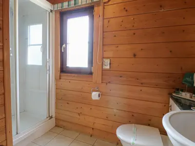 a bathroom with wooden walls and a toilet and a window at Heron Lodge in Langham
