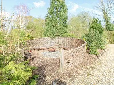 a wicker bench in the middle of a garden at Wagtail Lodge in Langham