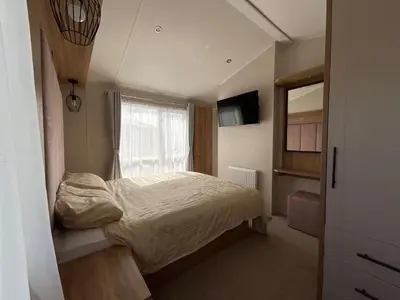 a small bedroom with a bed and a window at 2 bedroom Mini Lodge Caravan at Coopers Beach Holiday Park in East Mersea