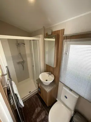 a small bathroom with a toilet and a sink at 2 bedroom Mini Lodge Caravan at Coopers Beach Holiday Park in East Mersea