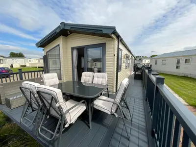 a deck with a table and chairs on a tiny house at 2 bedroom Mini Lodge Caravan at Coopers Beach Holiday Park in East Mersea