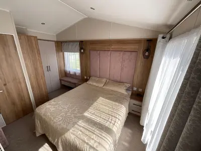 a small bedroom with a bed and a window at 2 bedroom Mini Lodge Caravan at Coopers Beach Holiday Park in East Mersea