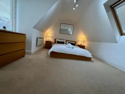 a attic bedroom with a bed and two night stands at St Nicolas Cottage in Ipswich