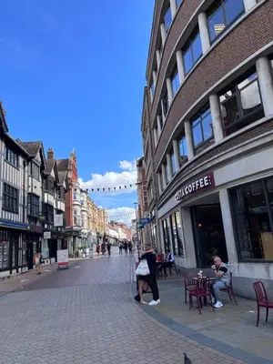a city street with people sitting at tables in front of buildings at St Nicolas Cottage in Ipswich