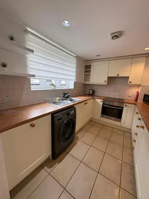 a kitchen with white cabinets and a dishwasher at St Nicolas Cottage in Ipswich