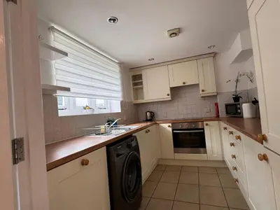 a kitchen with white cabinets and a dishwasher at St Nicolas Cottage in Ipswich