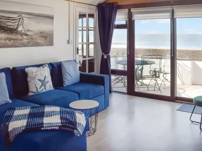 a living room with a blue couch and a view of the ocean at Angie's Beachside House in Brightlingsea