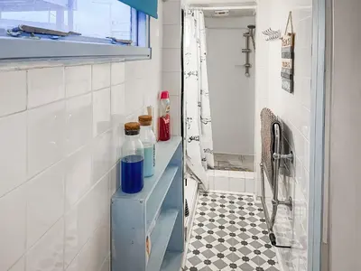 a bathroom with a shelf with bottles on it at Angie's Beachside House in Brightlingsea