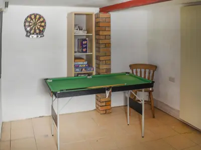 a room with a pool table and a chair at Angie's Beachside House in Brightlingsea