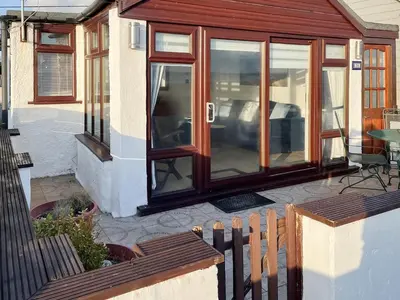 a house with glass doors and a patio at Angie's Beachside House in Brightlingsea