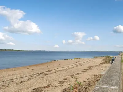 a sandy beach next to a body of water at Angie's Beachside House in Brightlingsea