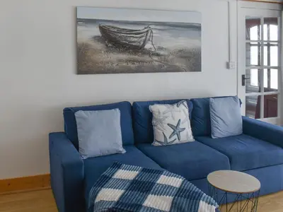 a blue couch in a living room with a painting at Angie's Beachside House in Brightlingsea