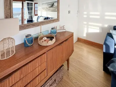 a living room with a wooden dresser with a mirror at Angie's Beachside House in Brightlingsea