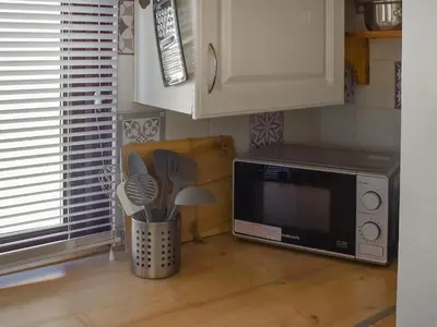 a kitchen with a microwave and a table with utensils at Angie's Beachside House in Brightlingsea