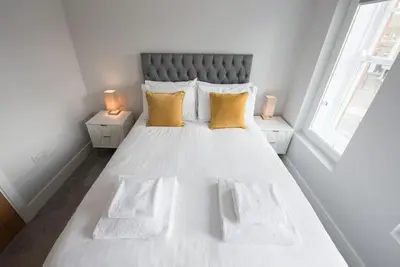 a bedroom with a large white bed with yellow pillows at Modern,Bright and spacious 2 bed in Brentwood