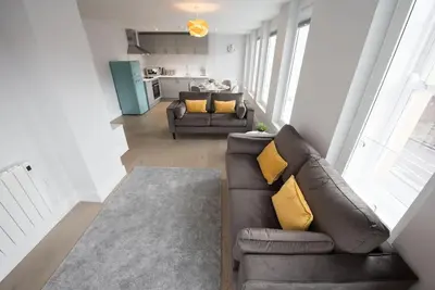a living room with a brown leather couch and yellow pillows at Modern,Bright and spacious 2 bed in Brentwood