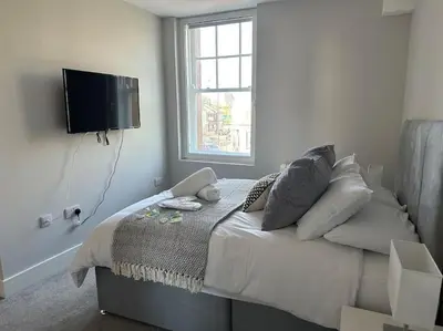 a bedroom with a bed with pillows and a flat screen tv at Bright, spacious 1 bedroom flat in Brentwood
