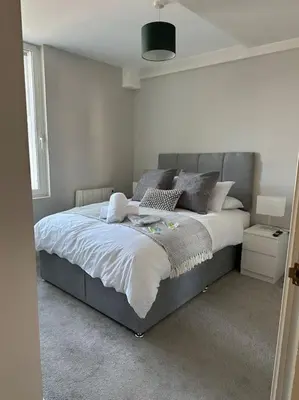 a bedroom with a bed with a gray headboard at Bright, spacious 1 bedroom flat in Brentwood