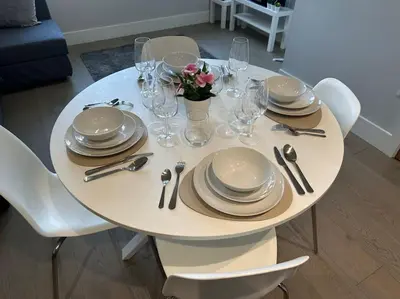 a white table with plates and glasses and flowers on it at Bright, spacious 1 bedroom flat in Brentwood