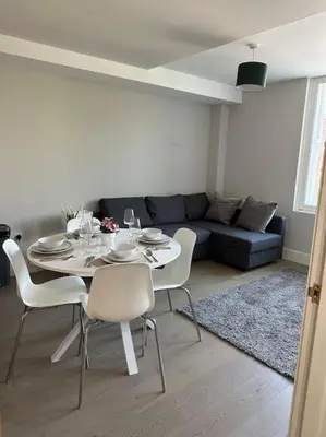 a table and chairs in a living room with a couch at Bright, spacious 1 bedroom flat in Brentwood