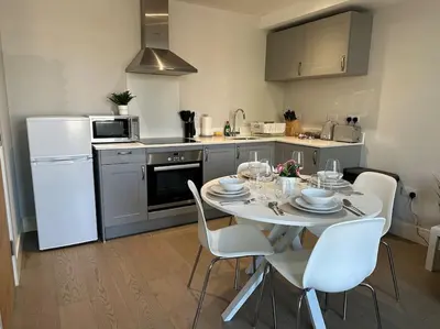 a kitchen with a table with white chairs and a white refrigerator at Bright, spacious 1 bedroom flat in Brentwood