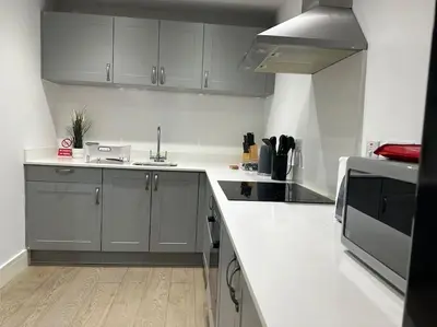 a kitchen with white cabinets and a white counter top at Bright, spacious and modern flat in Brentwood