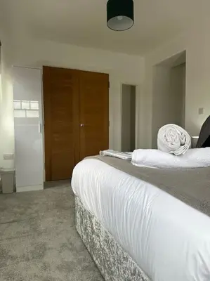 a bedroom with a bed with white sheets on it at Bright, spacious and modern flat in Brentwood
