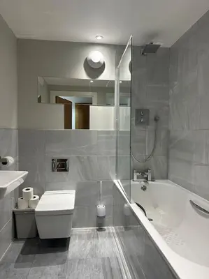 a bathroom with a tub and a toilet and a sink at Bright, spacious and modern flat in Brentwood