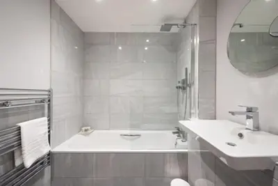 a white bathroom with a tub and a sink at Cosy, Bright and Spacious Flat in Brentwood
