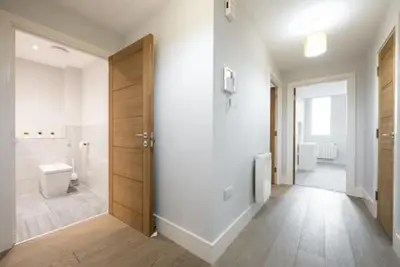 a white bathroom with a toilet and a door at Cosy, Bright and Spacious Flat in Brentwood