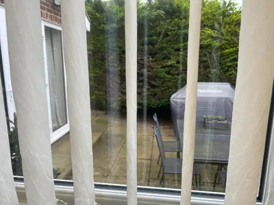 a window with a chair sitting on a patio at Cozy 3 bedroom bungalow in rural location in Ashwell