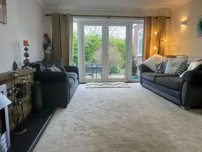a living room with two couches and a sliding glass door at Cozy 3 bedroom bungalow in rural location in Ashwell