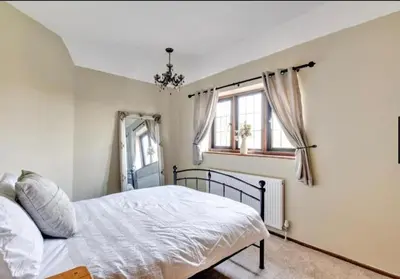 a bedroom with a bed and two windows at Home by the Sea in Clacton-on-Sea