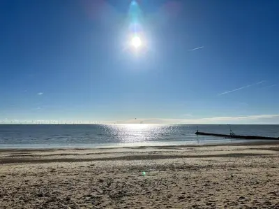 a beach with the sun rising over the water at Home by the Sea in Clacton-on-Sea
