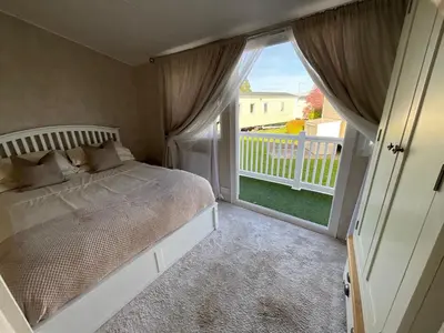 a bedroom with a bed and a large window at Seaview Caravan 2 Bedroom Sleeps 6 -WiFi -Smart Tv in Colchester
