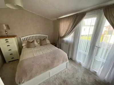 a bedroom with a bed and a large window at Seaview Caravan 2 Bedroom Sleeps 6 -WiFi -Smart Tv in Colchester