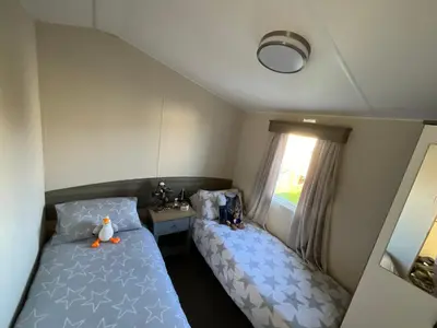a small bedroom with two beds and a window at Seaview Caravan 2 Bedroom Sleeps 6 -WiFi -Smart Tv in Colchester