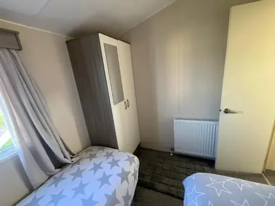 a small bedroom with a bed and a window at Seaview Caravan 2 Bedroom Sleeps 6 -WiFi -Smart Tv in Colchester