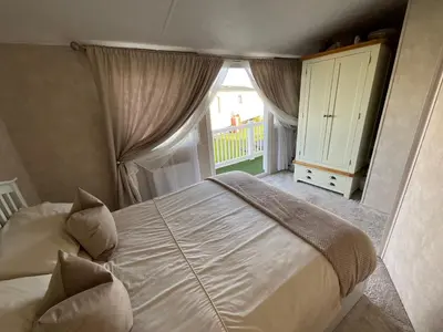a bedroom with a large bed and a window at Seaview Caravan 2 Bedroom Sleeps 6 -WiFi -Smart Tv in Colchester