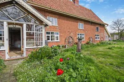 a brick house with red flowers in front of it at 3 Bed in Rumburgh oc-c27094 in Rumburgh