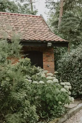 a brick house with a garden with white flowers at Restaries at Paradise Farm in Halesworth