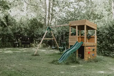 a playground with a slide and a play tower at Restaries at Paradise Farm in Halesworth
