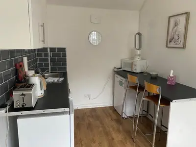 a kitchen with a counter with chairs and a microwave at The Dairy in Takeley