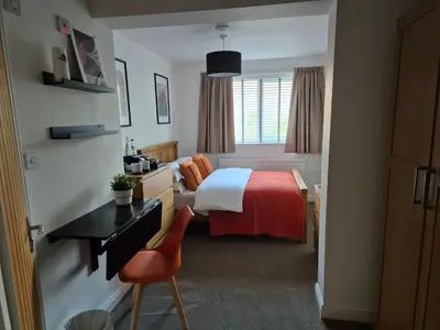 a hotel room with a bed with a desk and a chair at Carolines rooms in Cherry Hinton