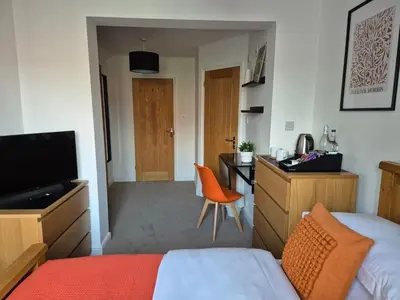 a bedroom with a bed and a desk with a television at Carolines rooms in Cherry Hinton