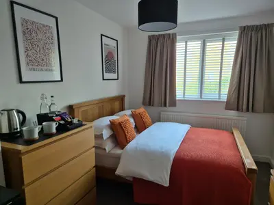 a bedroom with a bed and a dresser and a window at Carolines rooms in Cherry Hinton